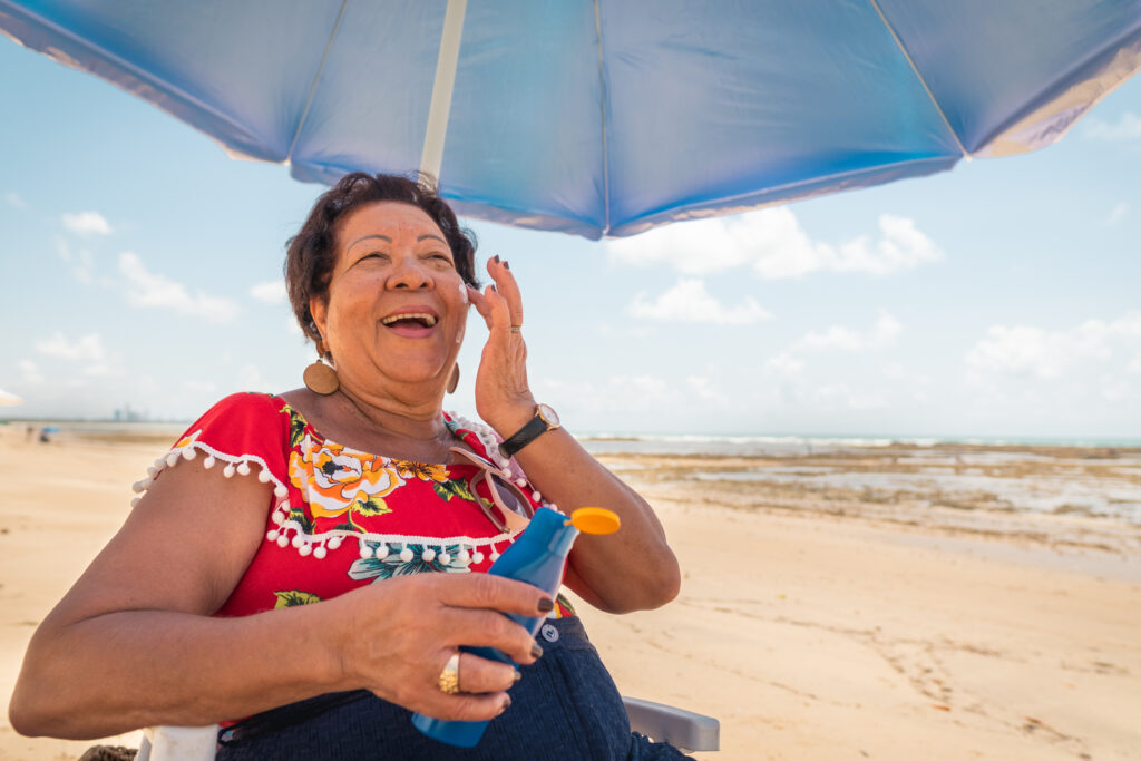 Elderly Woman Using Suntan Lotion on Beach