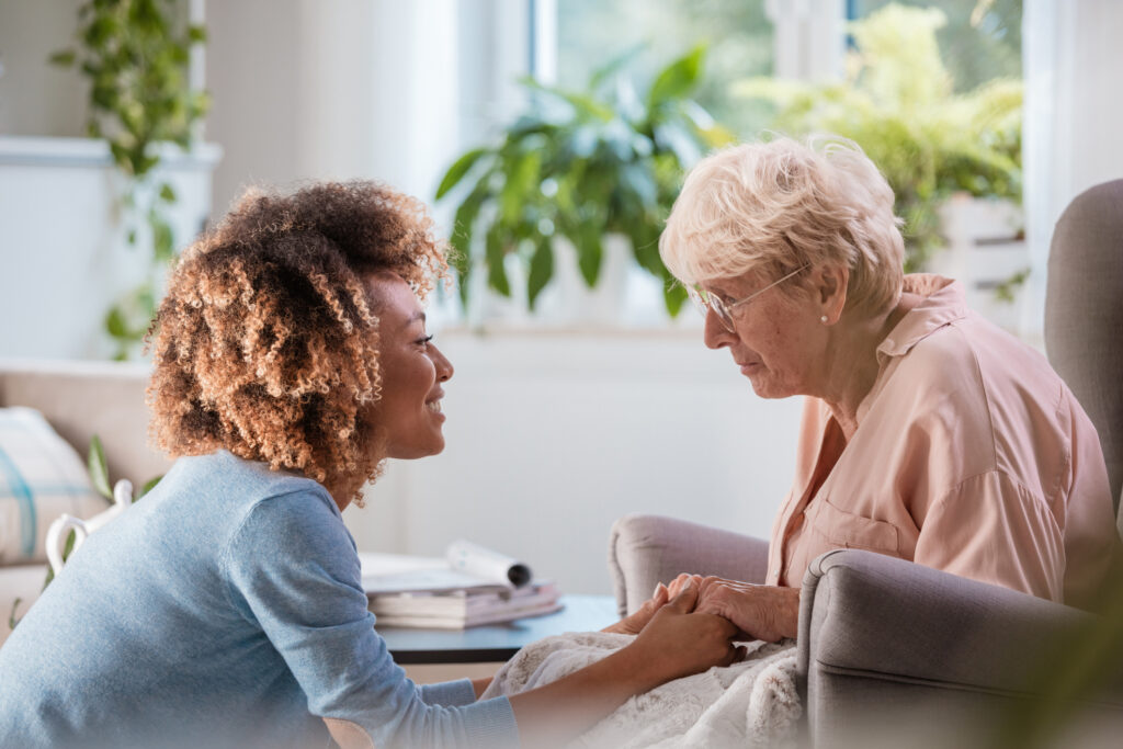 Cheerful home caregiver consoling senior woman