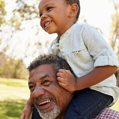 Grandson sitting on grandfather's shoulders